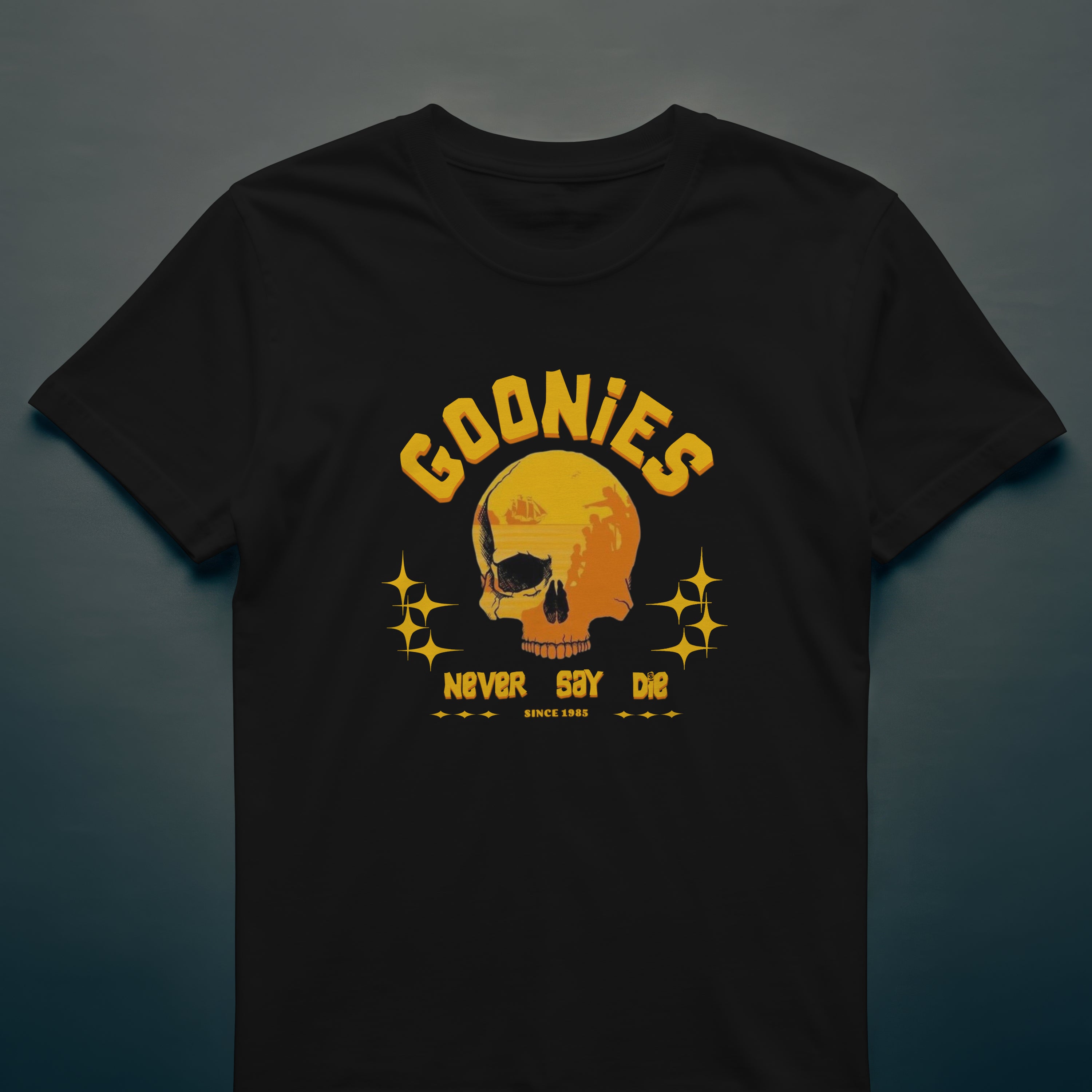 Black t-shirt with yellow skull graphic and 'Goonies Never Say Die' text on a dark background